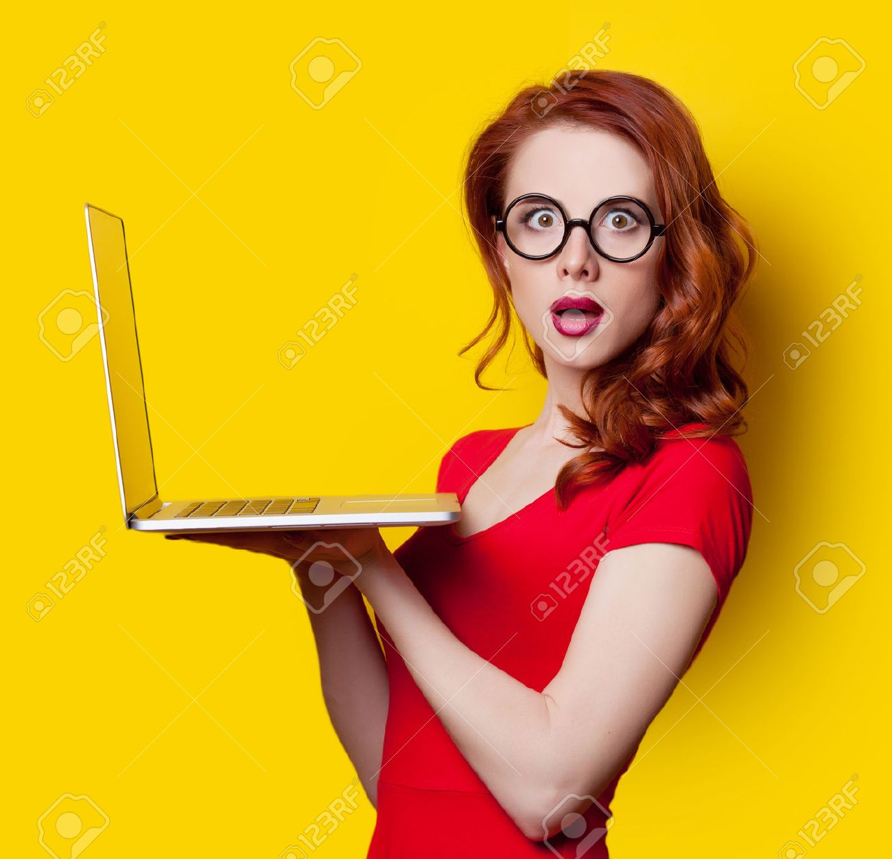 Surprised redhead girl with laptop computer in red dress on yellow background. - 40455024 Surprised redhead girl with laptop computer in red dress on yellow background. - 40455024