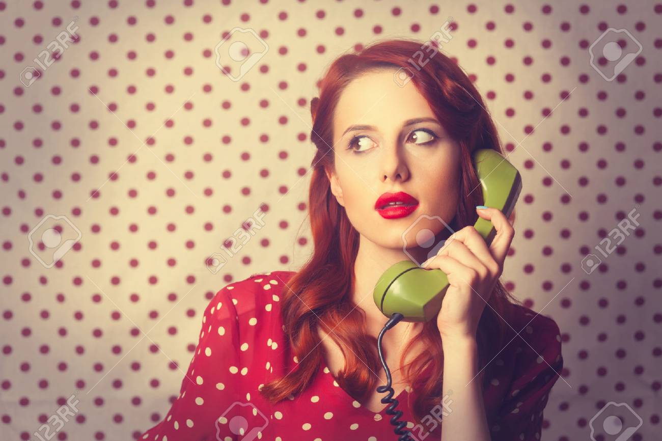 Portrait of a redhead girl with green dial phone on Polka dot background. - 41552151 Portrait of a redhead girl with green dial phone on Polka dot background. - 41552151