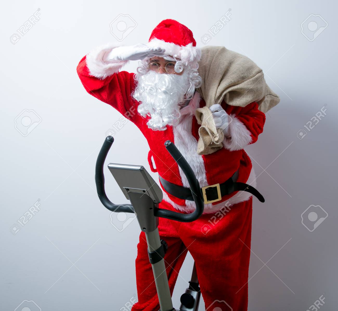 Immagini Babbo Natale In Bicicletta.Immagini Stock Divertente Babbo Natale Hanno Un Divertimento Con Le Bici Di Esercitazione Su Priorita Bassa Bianca Image 81049179