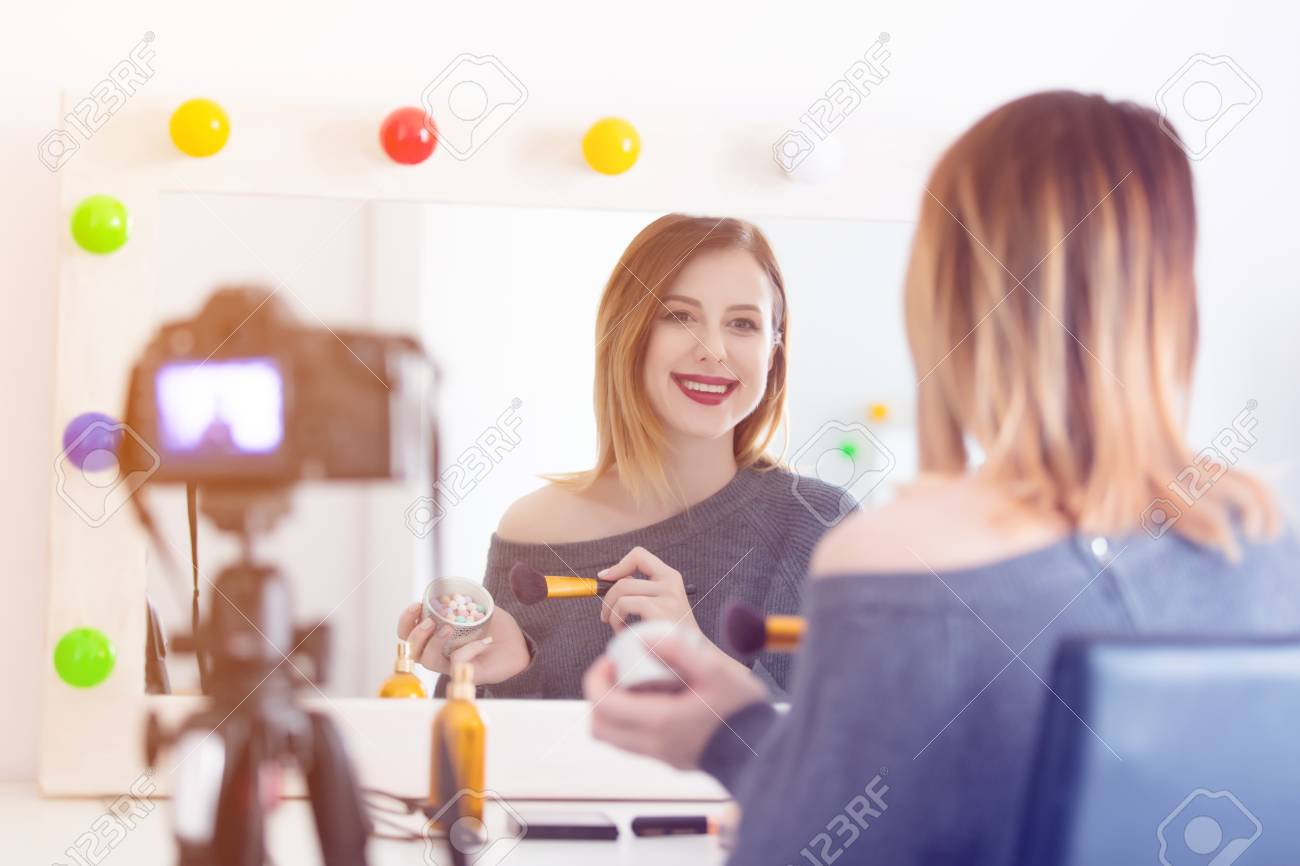 動画共有サイトのためのカメラで化粧品を適用する若い白人ブロガーの女性 ミラー付近のホームの場所 の写真素材 画像素材 Image