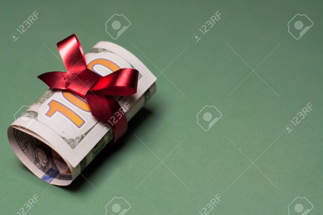 rolled u s one hundred dollar bill tied with red ribbon and