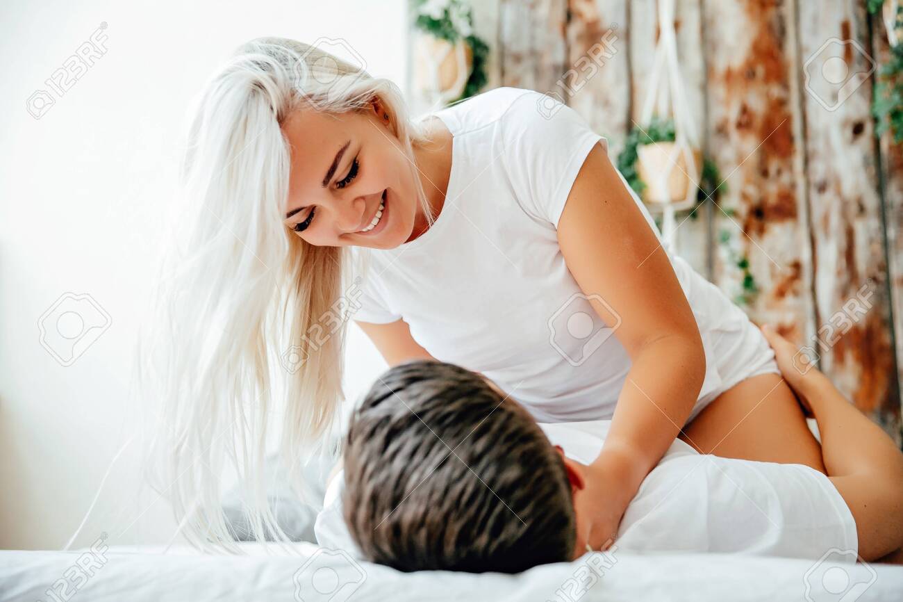 Woman on top of man in intimate bedroom embrace