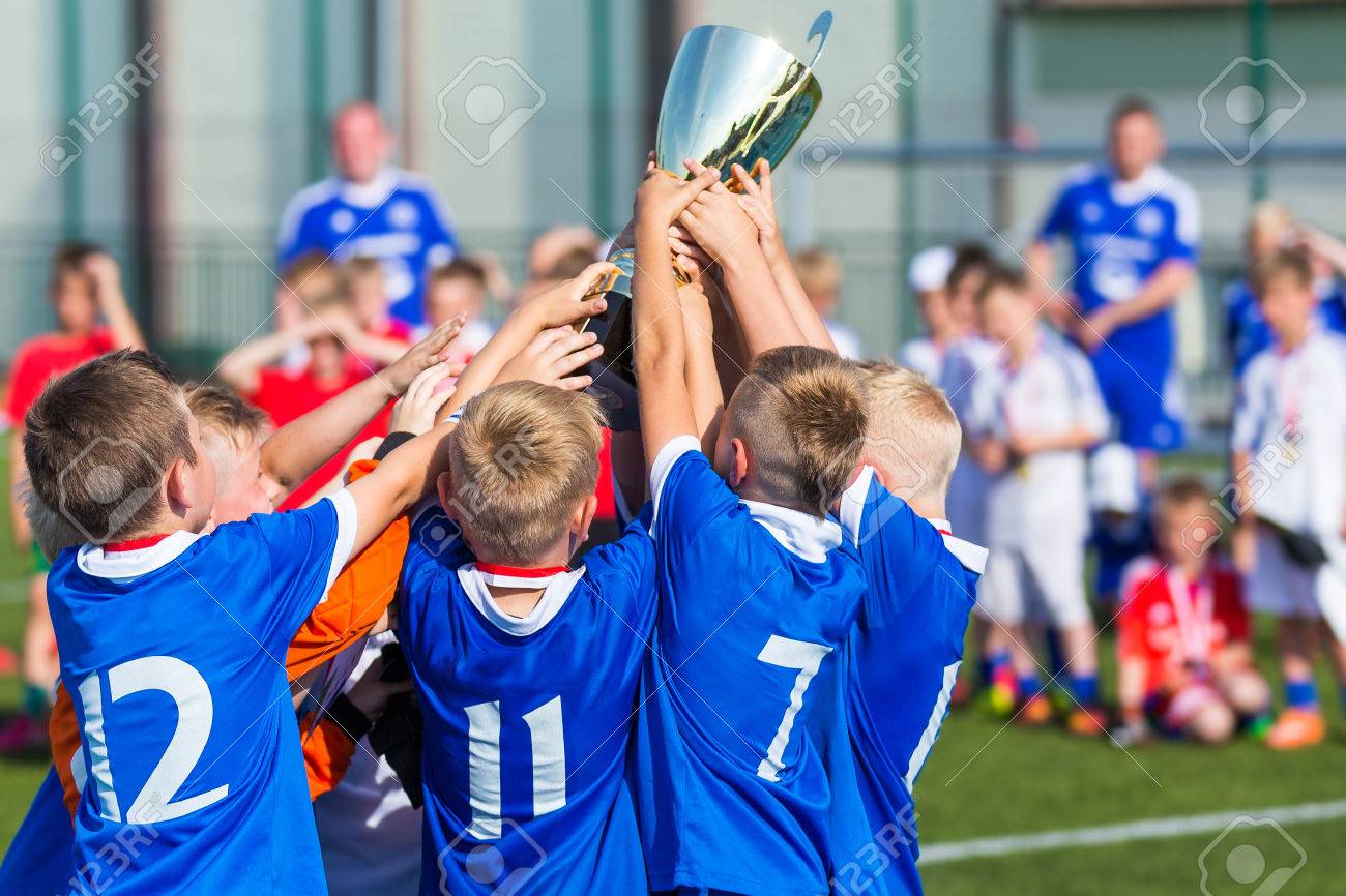 Young Soccer Players Holding Trophy. Boys Celebrating Soccer Football Championship. Winning team of sport tournament for kids children. - 51539211 Young Soccer Players Holding Trophy. Boys Celebrating Soccer Football Championship. Winning team of sport tournament for kids children. - 51539211