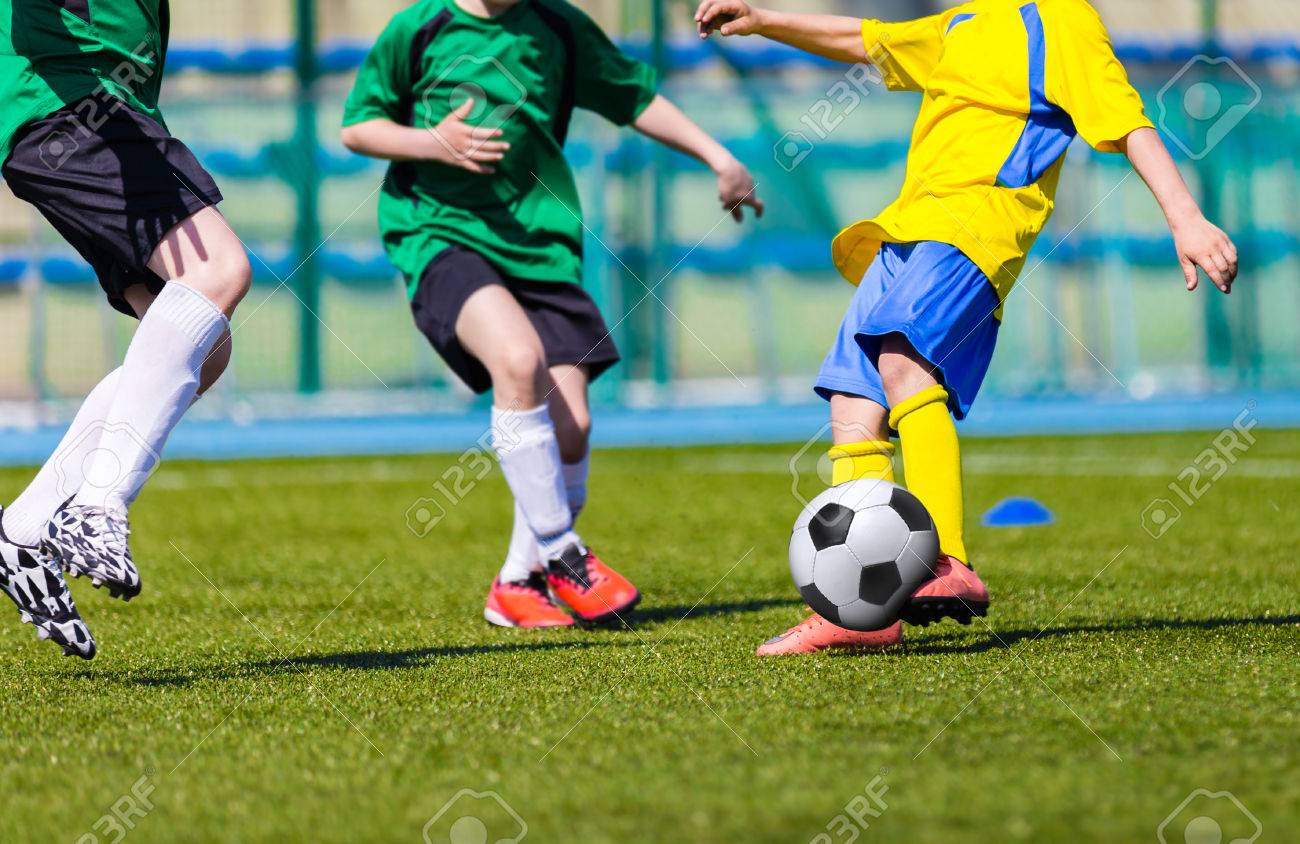 少年サッカー サッカー ゲーム 緑と黄色のユニフォームで選手を実行します の写真素材 画像素材 Image