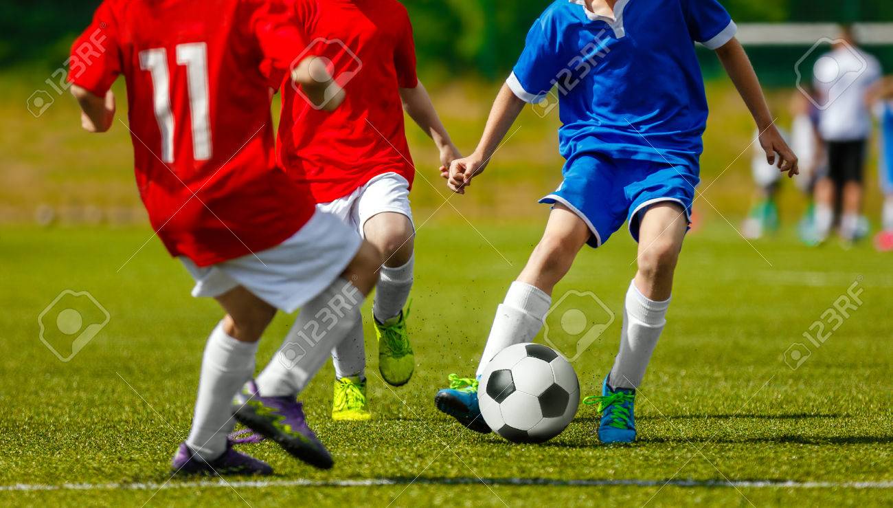 天然芝のピッチでサッカー スポーツを遊んでいる子供たち 芝生の上のボールを蹴る少年青と赤のサッカーユニ フォーム 子供のサッカーの試合 の写真素材 画像素材 Image