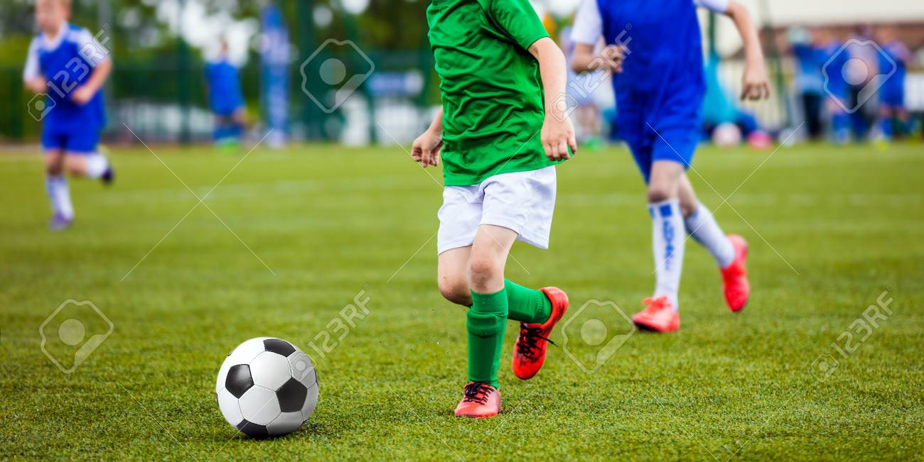 Jogo De Futebol. Crianças Jogando Futebol. Meninos Jovens Chutando Bola De  Futebol No Campo De Esportes. Crianças Jogando Jogo De Torneio De Futebol  No Campo. Juventude Jogo De Futebol Europeu Foto Royalty