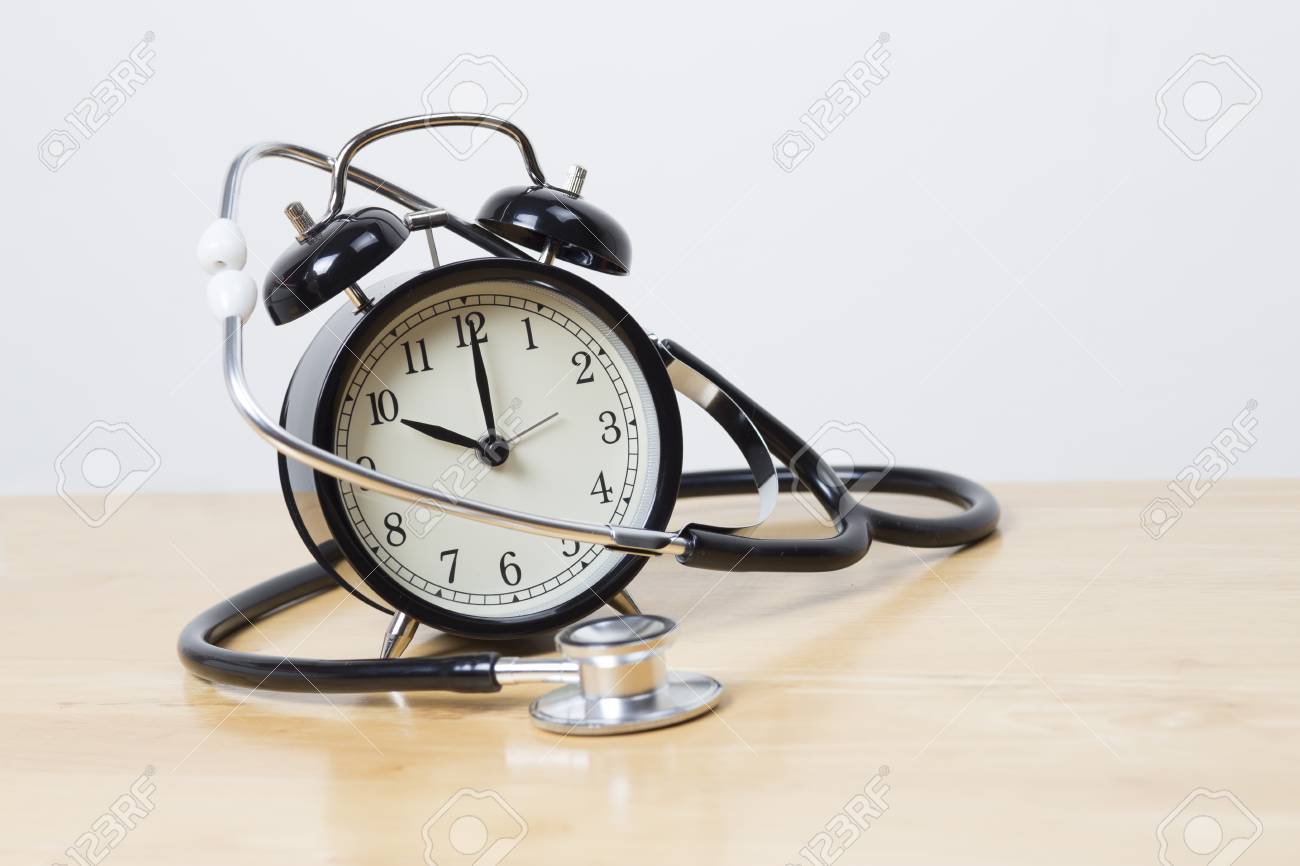 stethoscope and bell alarm clock on wooden table stock photo