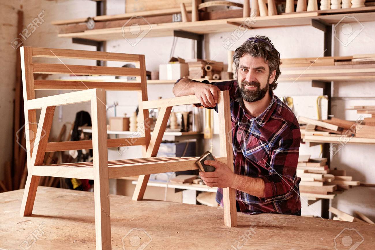 portrait of an artisan designer with new piece of furniture furniture designer
