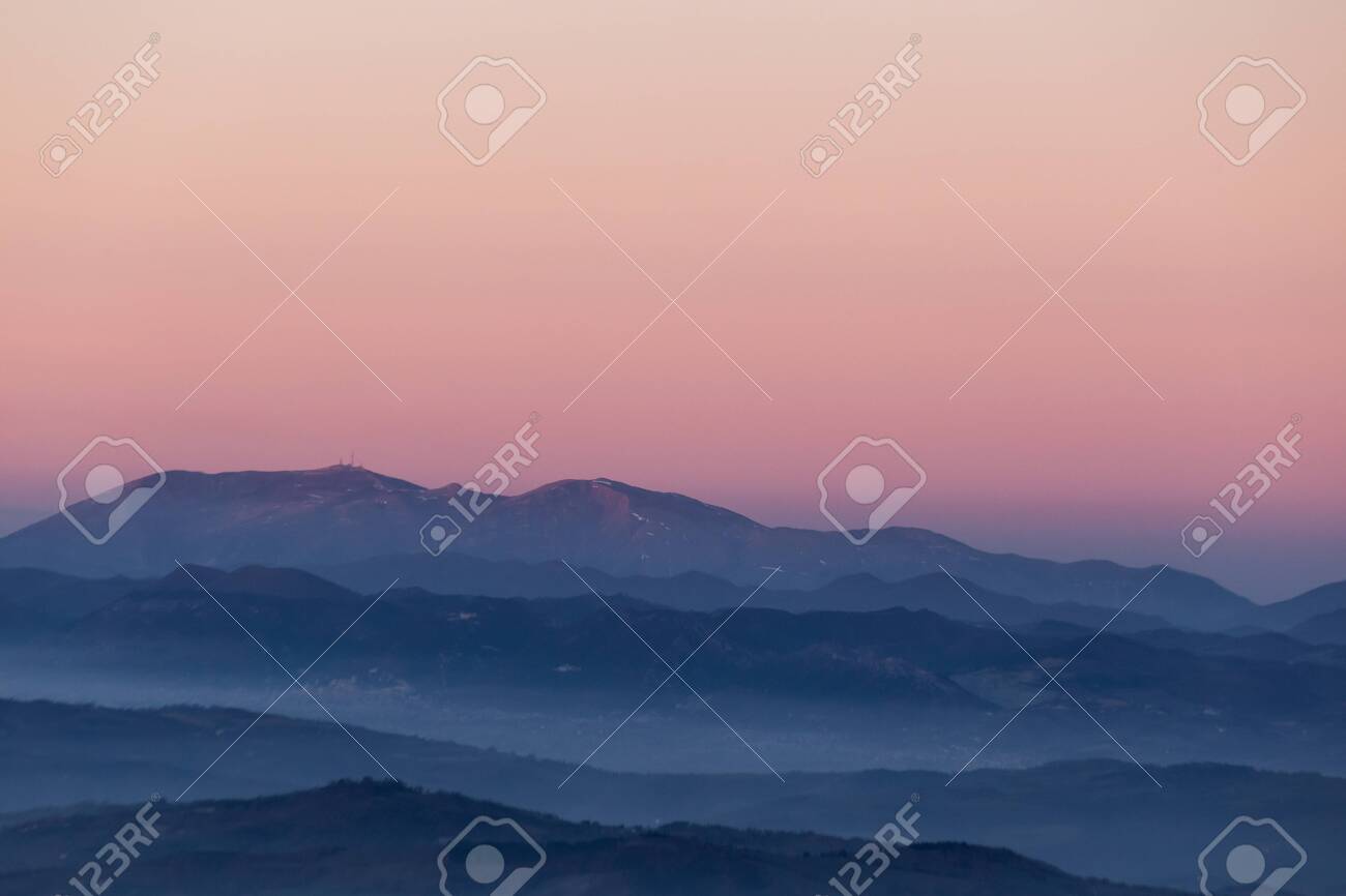 Beautifully colored sky at dusk, with mountains layers and mist between them - 122261164 Beautifully colored sky at dusk, with mountains layers and mist between them - 122261164