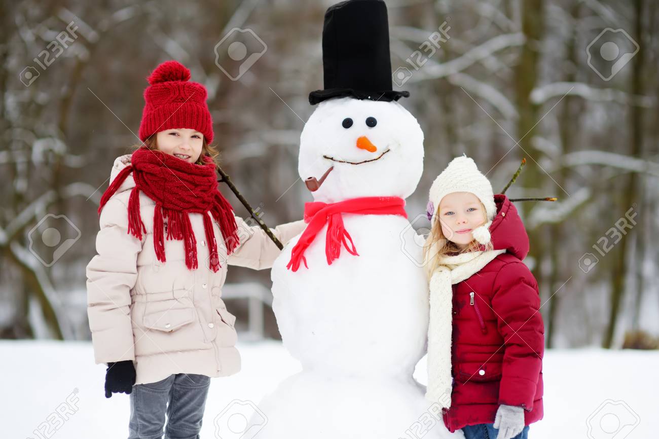 美しい冬の公園で一緒に雪だるまを構築 2 人の愛らしい少女 かわいい姉妹が 雪で遊ぶ 子供のための冬の活動 の写真素材 画像素材 Image