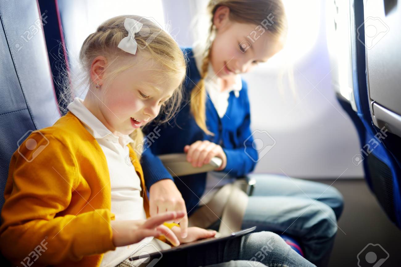 愛らしい女の子が飛行機で旅行します デジタル タブレットを使用して飛行中に航空機ウィンドウで座っている子供 子供と海外旅行 の写真素材 画像素材 Image
