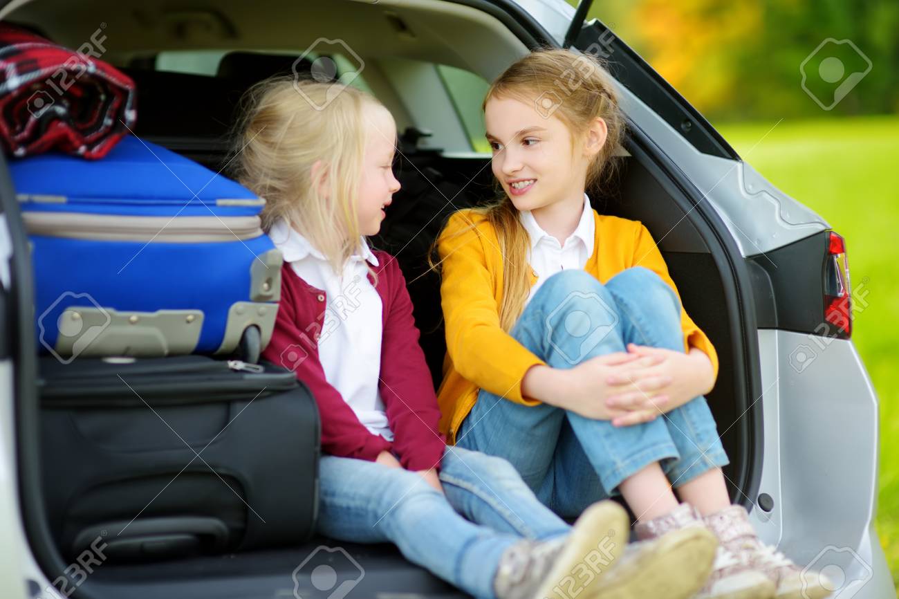 両親と休暇に行く前に車の中に座っている2人の愛らしい小さな女の子 ロードトリップや旅行を楽しみにしている2人の子供 車での家族旅行 の写真素材 画像素材 Image