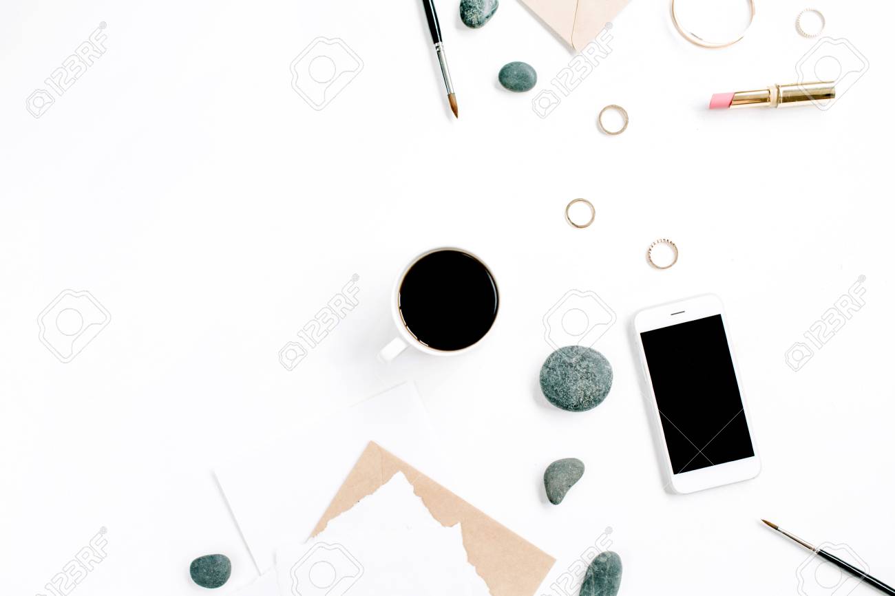 Espace de travail de bureau à domicile avec café, téléphone portable, enveloppe de bricolage, pierres, écouteurs et papier vierge sur fond blanc Lay Espace de travail de bureau à domicile avec café, téléphone portable, enveloppe de bricolage, pierres, écouteurs et papier vierge sur fond blanc Lay