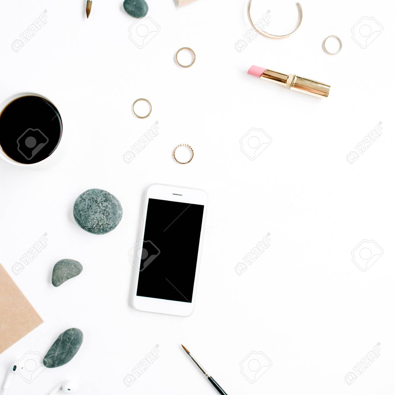 Espace de travail de bureau à domicile avec café, téléphone portable, enveloppe de bricolage, pierres, écouteurs et papier vierge sur fond blanc Lay Espace de travail de bureau à domicile avec café, téléphone portable, enveloppe de bricolage, pierres, écouteurs et papier vierge sur fond blanc Lay