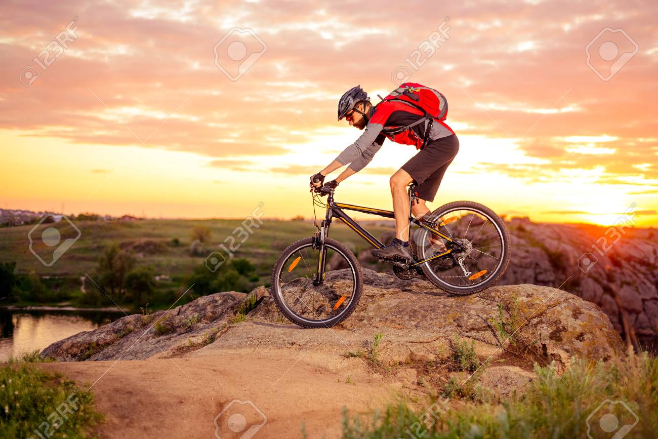 Cyclist Riding the Bike Down Hill on the Mountain Rocky Trail at Sunset. Extreme Sports - 61049121 Cyclist Riding the Bike Down Hill on the Mountain Rocky Trail at Sunset. Extreme Sports - 61049121
