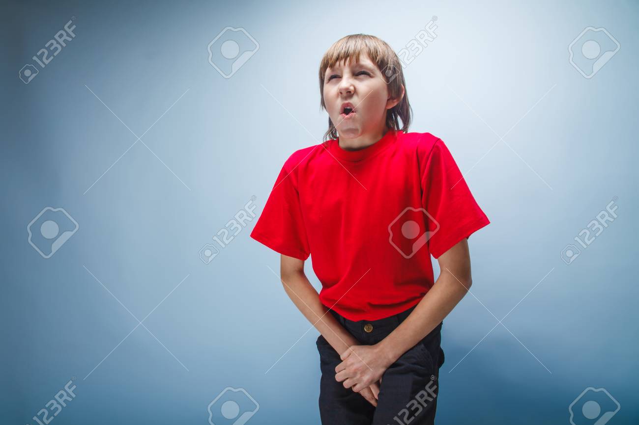 赤い T シャツ ヨーロッパの外観の茶色の髪は灰色の背景に彼の股間を押し手のティーンエイ ジャーの男の子が 優しさに口を開けてください の写真素材 画像素材 Image