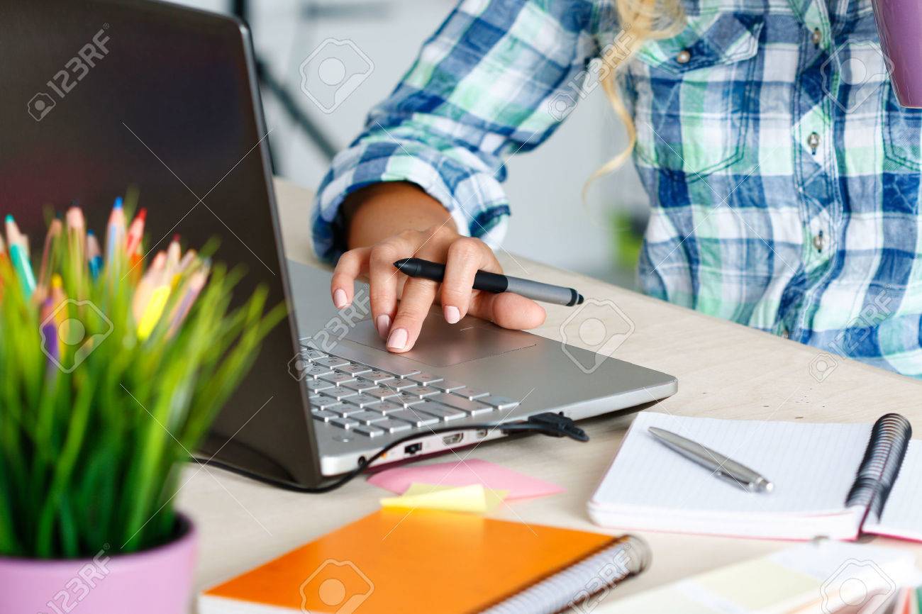 Hands of female designer in office working with digital graphic tablet and laptop. Photography retoucher sitting at desk and looking in display. Creative people or advertising business concept - 47600488 Hands of female designer in office working with digital graphic tablet and laptop. Photography retoucher sitting at desk and looking in display. Creative people or advertising business concept - 47600488