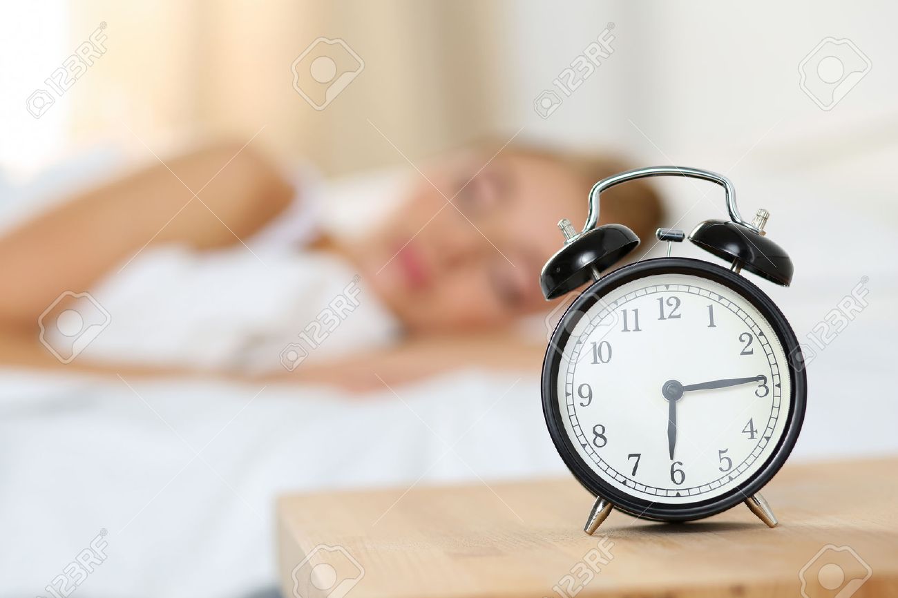alarm clock standing on bedside table going to ring early morning