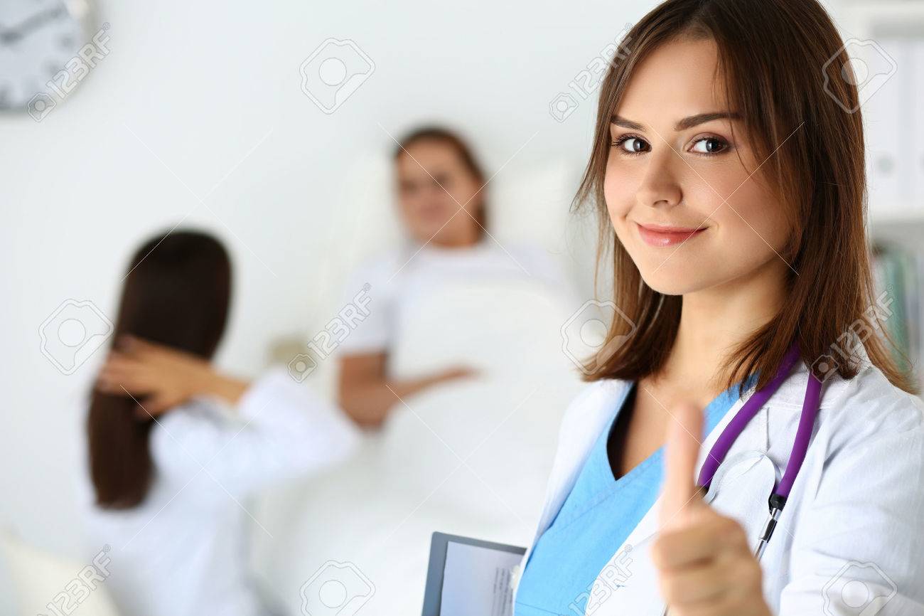Smiling female medicine doctor holding document pad and showing OK sign with thumb up at ward wile round. High level and quality medical service concept. Best treatment and patient care concept - 49794212 Smiling female medicine doctor holding document pad and showing OK sign with thumb up at ward wile round. High level and quality medical service concept. Best treatment and patient care concept - 49794212