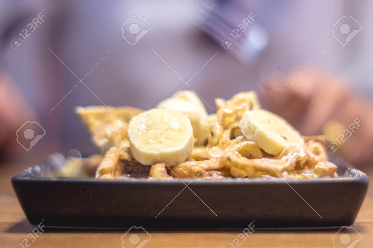 トーストは スライスしたバナナ ナッツ 卵 クリーム チーズ ソースをトッピングします トーストといくつかの選択的なフォーカスを持つフィールドの浅い深さの極端なぼかしプレートのコーナー 女性 男の食べ方 フォークを使用して の写真素材 画像素材 Image