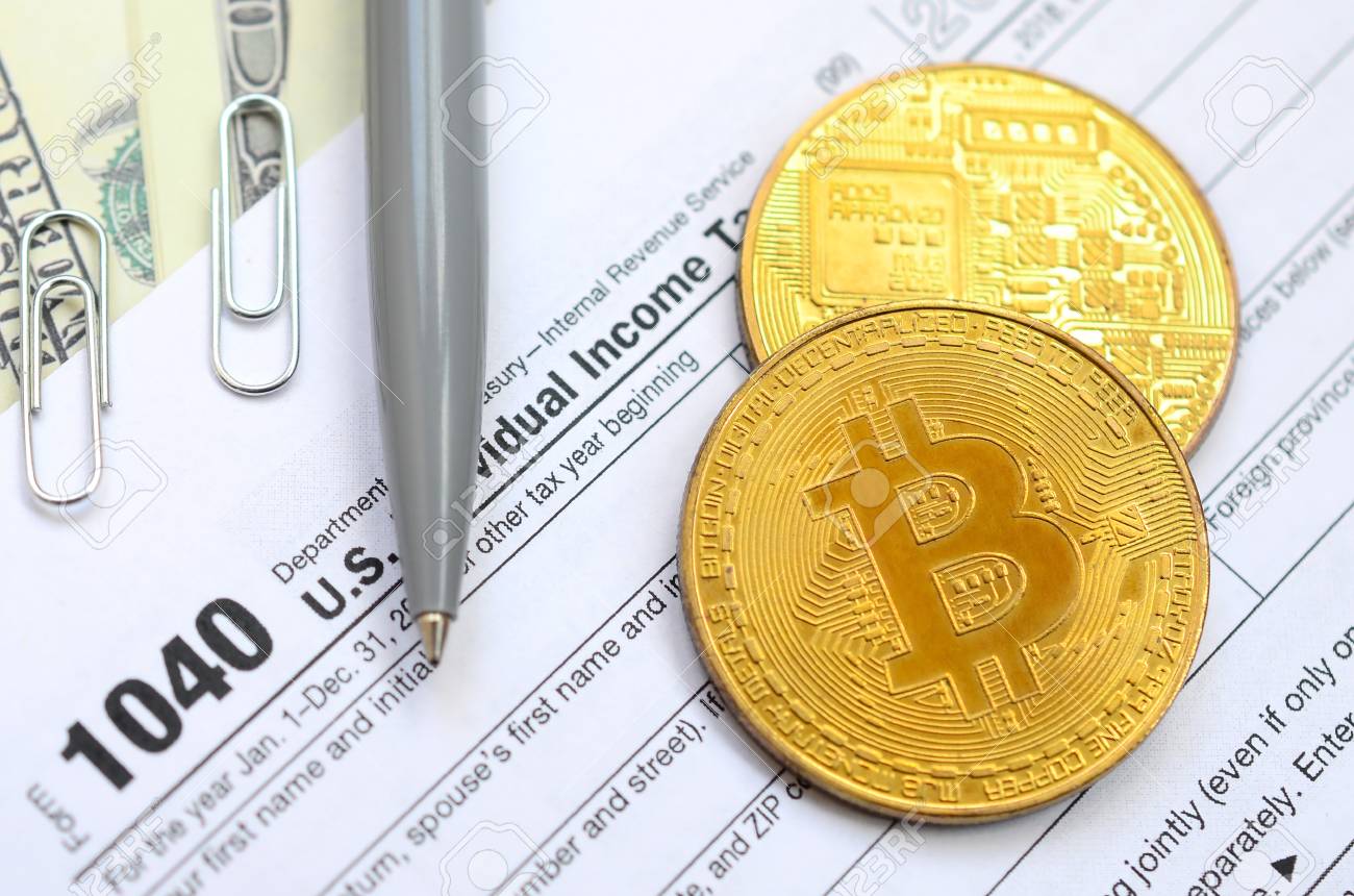 펜, 비트코인 및 달러 지폐는 세금 양식 1040 미국 개인 소득세 신고서에 있습니다. 세금을 내는 시간 로열티 무료 사진, 그림,  이미지 그리고 스톡포토그래피. Image 100227390