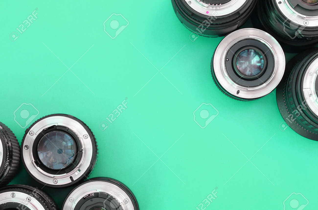 Several photographic lenses lie on a bright turquoise background. Space for text - 167450148 Several photographic lenses lie on a bright turquoise background. Space for text - 167450148