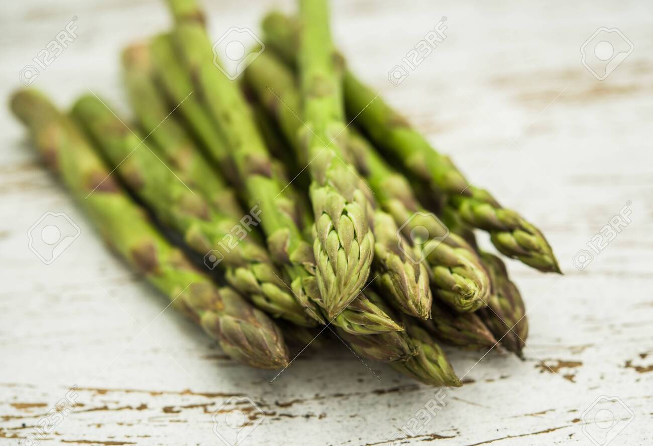 Close up of a bunch of asparagus against white wooden background - 136017361 Close up of a bunch of asparagus against white wooden background - 136017361