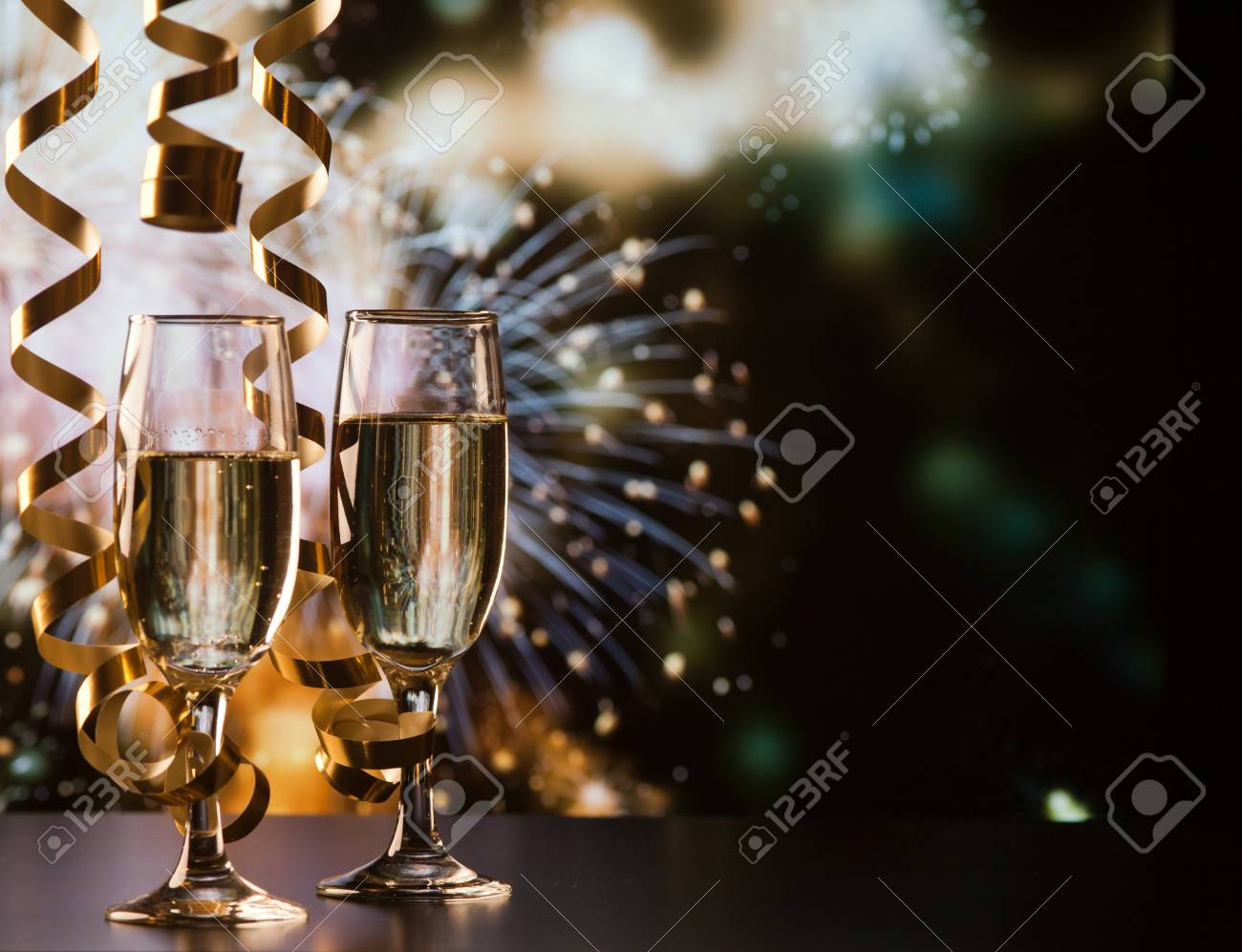 two champagne glasses with ribbons against holiday lights and fireworks - New Year celebrations - 89396104 two champagne glasses with ribbons against holiday lights and fireworks - New Year celebrations - 89396104