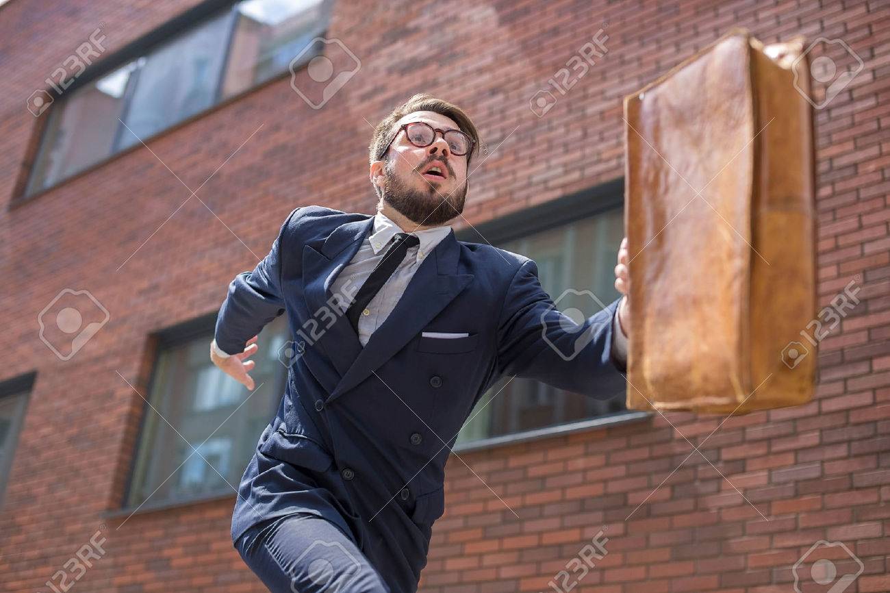 Young businessman with a briefcase and glasses running in a city street on a background of red brick wall. concept of rapid career - 43989911 Young businessman with a briefcase and glasses running in a city street on a background of red brick wall. concept of rapid career - 43989911