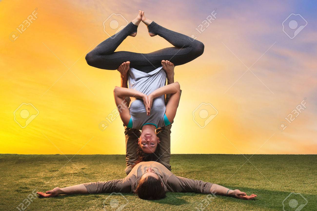 The two people doing yoga exercises against sunset sky The two people doing yoga exercises against sunset sky