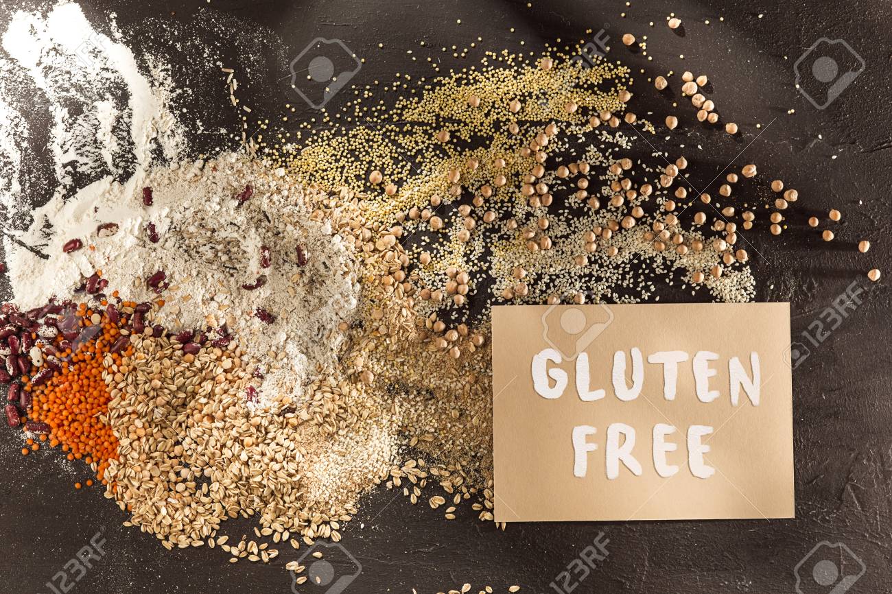 Gluten free flour and cereals millet, quinoa, corn bread, brown buckwheat, rice, bread and pasta with text gluten free in English language with spoon on wooden background, top view - 113941751 Gluten free flour and cereals millet, quinoa, corn bread, brown buckwheat, rice, bread and pasta with text gluten free in English language with spoon on wooden background, top view - 113941751