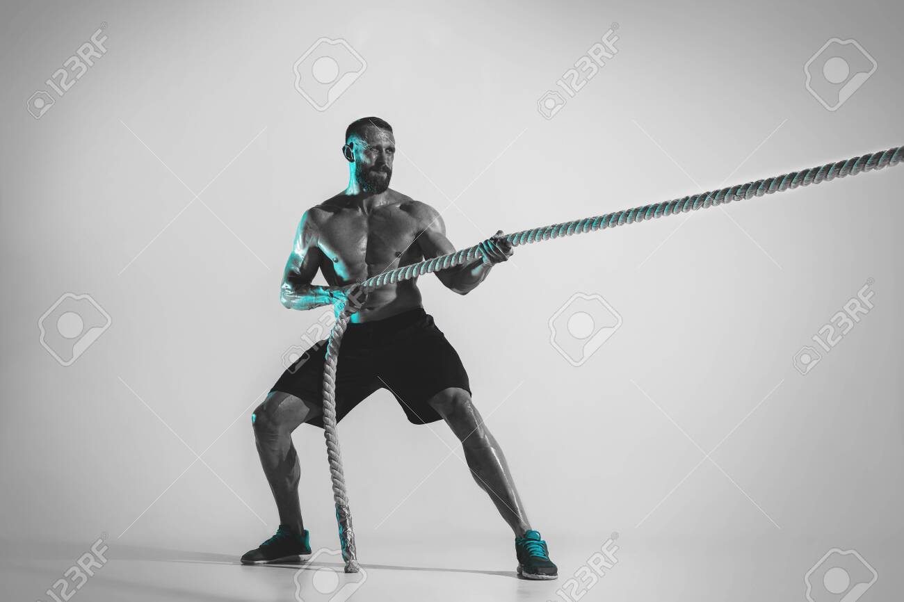 Comparison of forces. Young caucasian bodybuilder training over studio background in neon light. Muscular male model with the rope. Concept of sport, bodybuilding, healthy lifestyle, motion and action. - 124596081 Comparison of forces. Young caucasian bodybuilder training over studio background in neon light. Muscular male model with the rope. Concept of sport, bodybuilding, healthy lifestyle, motion and action. - 124596081