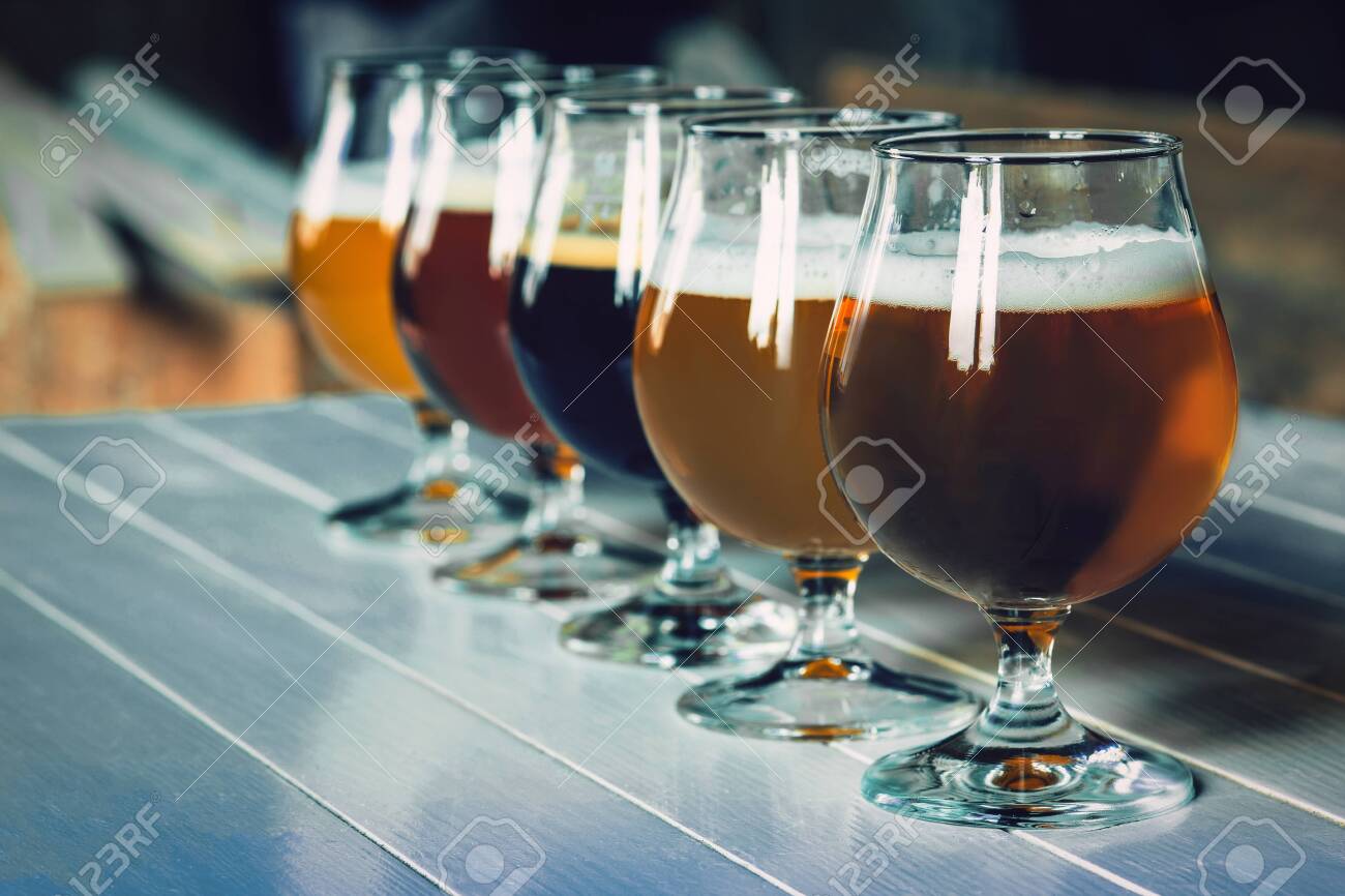 Glasses of different kinds of dark and light beer on wooden table in line. Cold delicious drinks are prepared for a big friends party. Concept of drinks, fun, meeting, oktoberfest. - 127691520 Glasses of different kinds of dark and light beer on wooden table in line. Cold delicious drinks are prepared for a big friends party. Concept of drinks, fun, meeting, oktoberfest. - 127691520