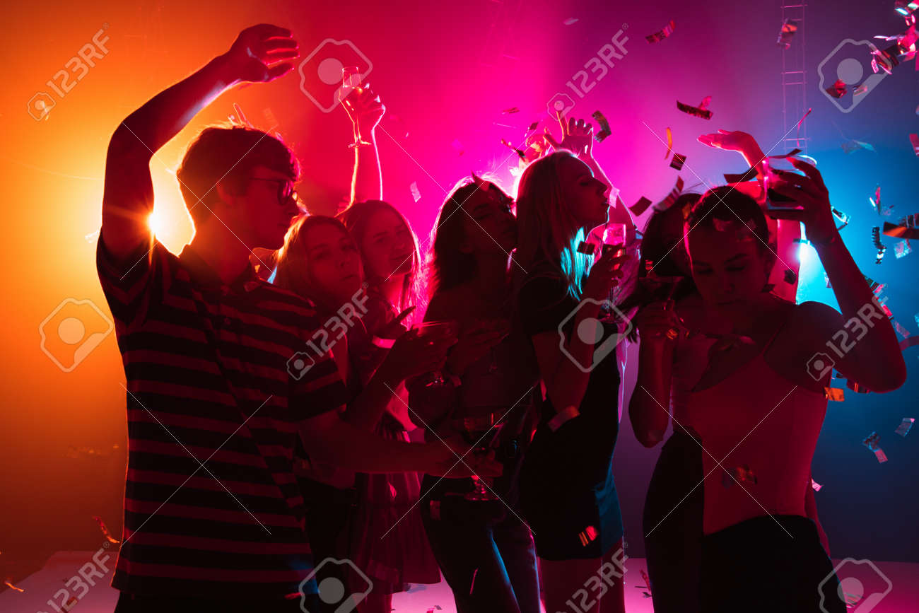 Wild. A crowd of people in silhouette raises their hands, dancing on dancefloor on neon light background. Night life, club, music, dance, motion, youth. Bright colors and moving girls and boys. - 155316874 Wild. A crowd of people in silhouette raises their hands, dancing on dancefloor on neon light background. Night life, club, music, dance, motion, youth. Bright colors and moving girls and boys. - 155316874