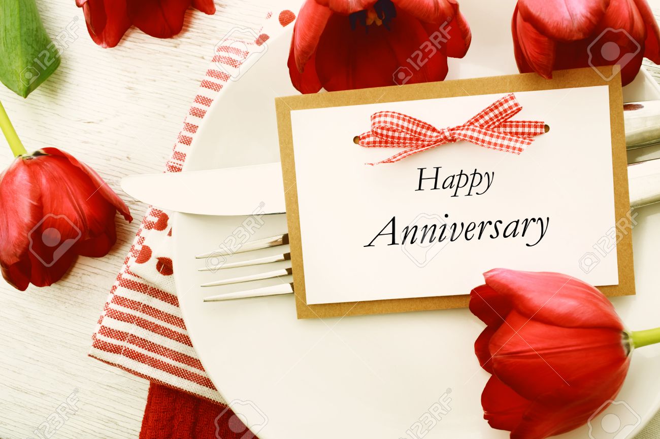 dinner table setting with happy anniversary message card and stock