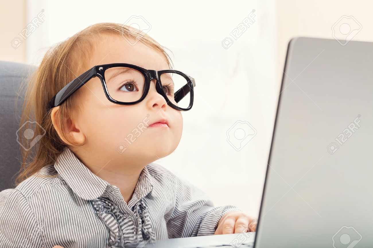 Smart little toddler girl wearing big glasses while using her laptop - 52412801 Smart little toddler girl wearing big glasses while using her laptop - 52412801