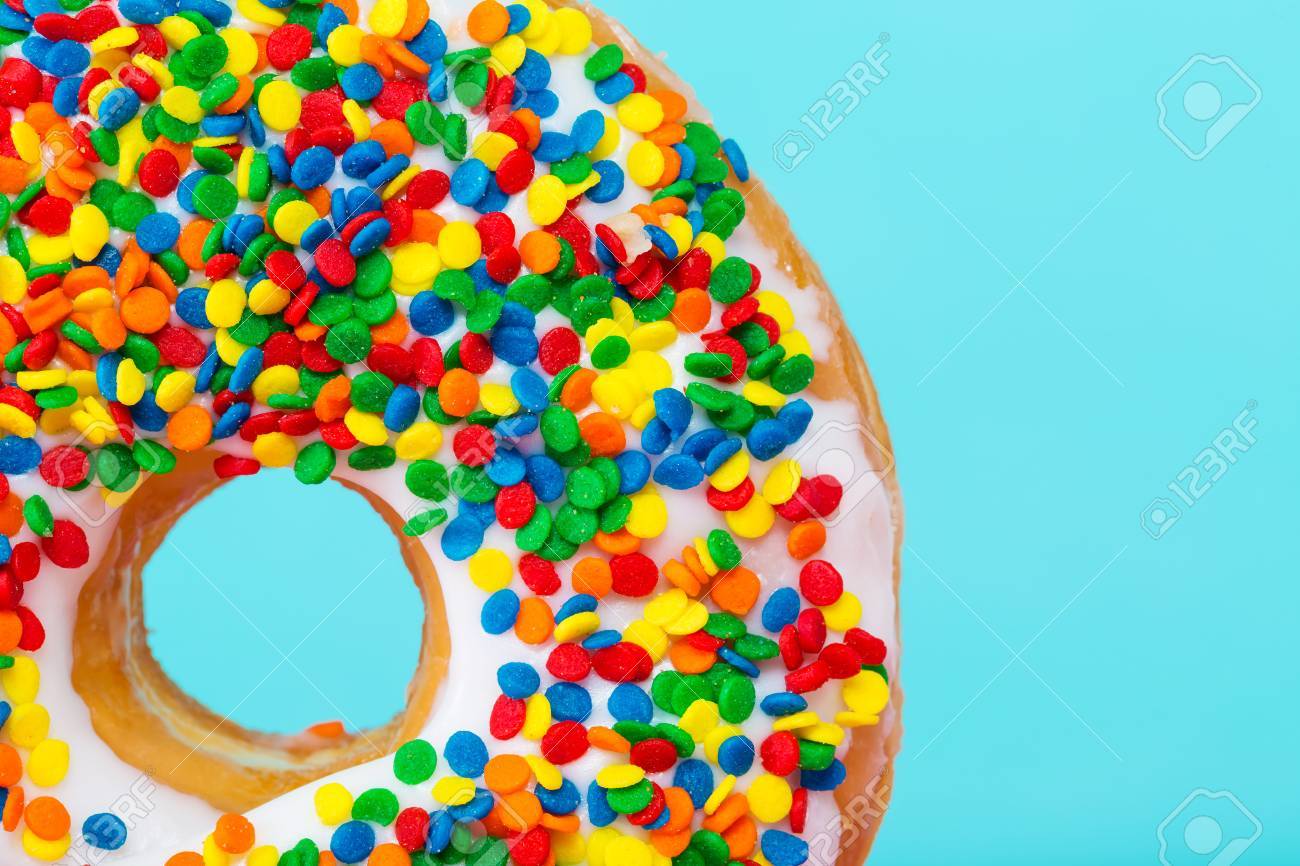 Close-up section of a sprinkled donut on pastel blue background - 53024661 Close-up section of a sprinkled donut on pastel blue background - 53024661