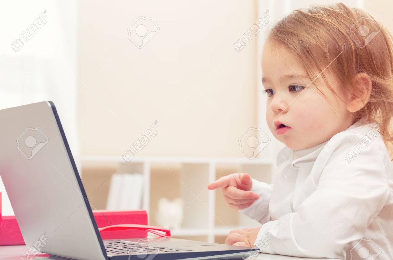 Happy toddler girl working on her laptop - 53677642 Happy toddler girl working on her laptop - 53677642