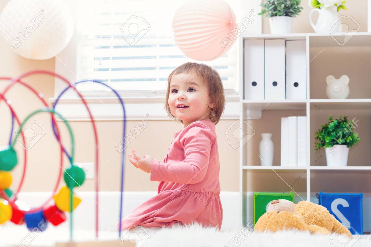 Happy toddler girl playing with toys in her house - 54659952 Happy toddler girl playing with toys in her house - 54659952