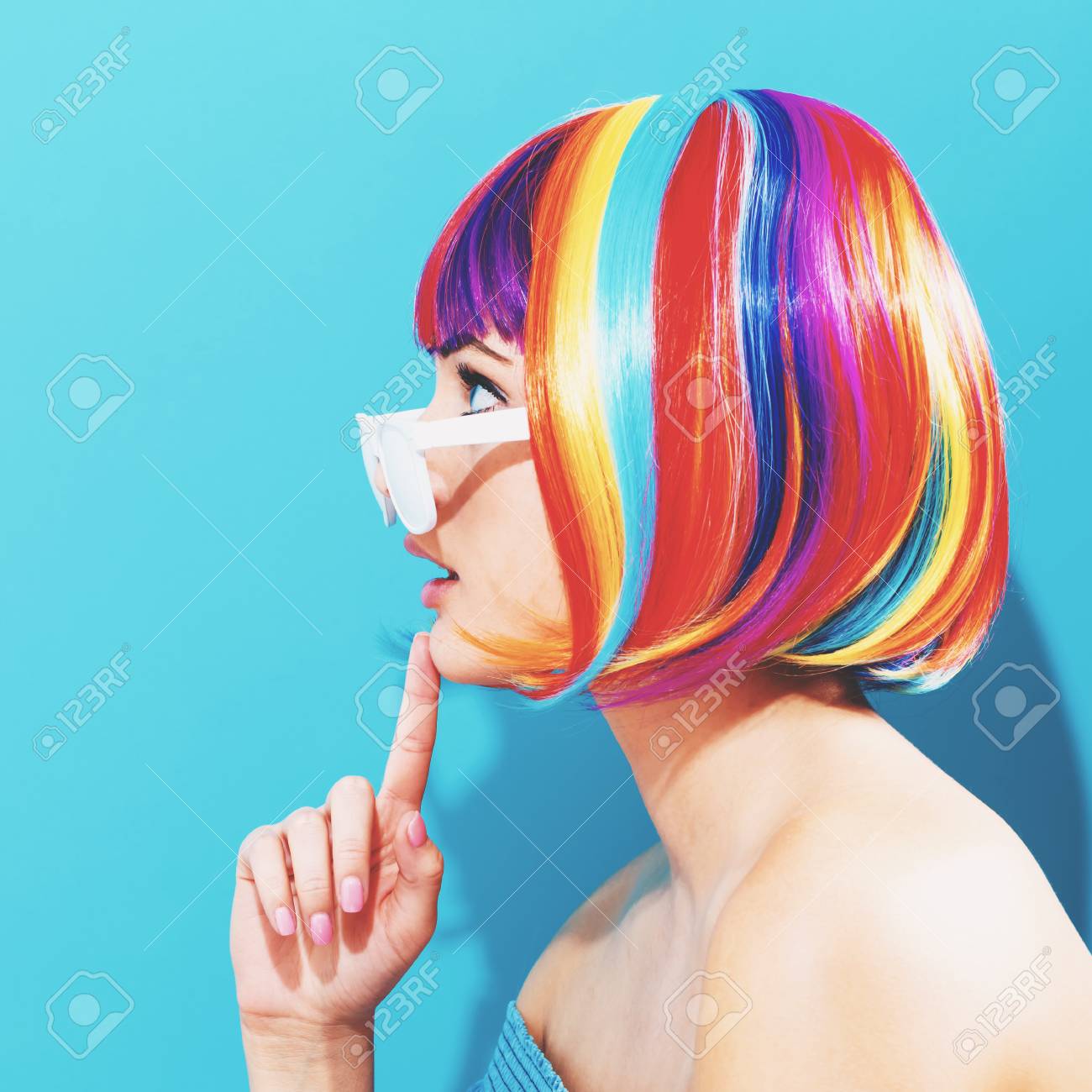 青色の背景にカラフルなウィッグで美しい女性の写真素材・画像素材