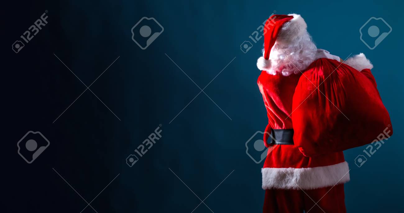 Santa holding a red sack on a dark blue background - 111825891 Santa holding a red sack on a dark blue background - 111825891