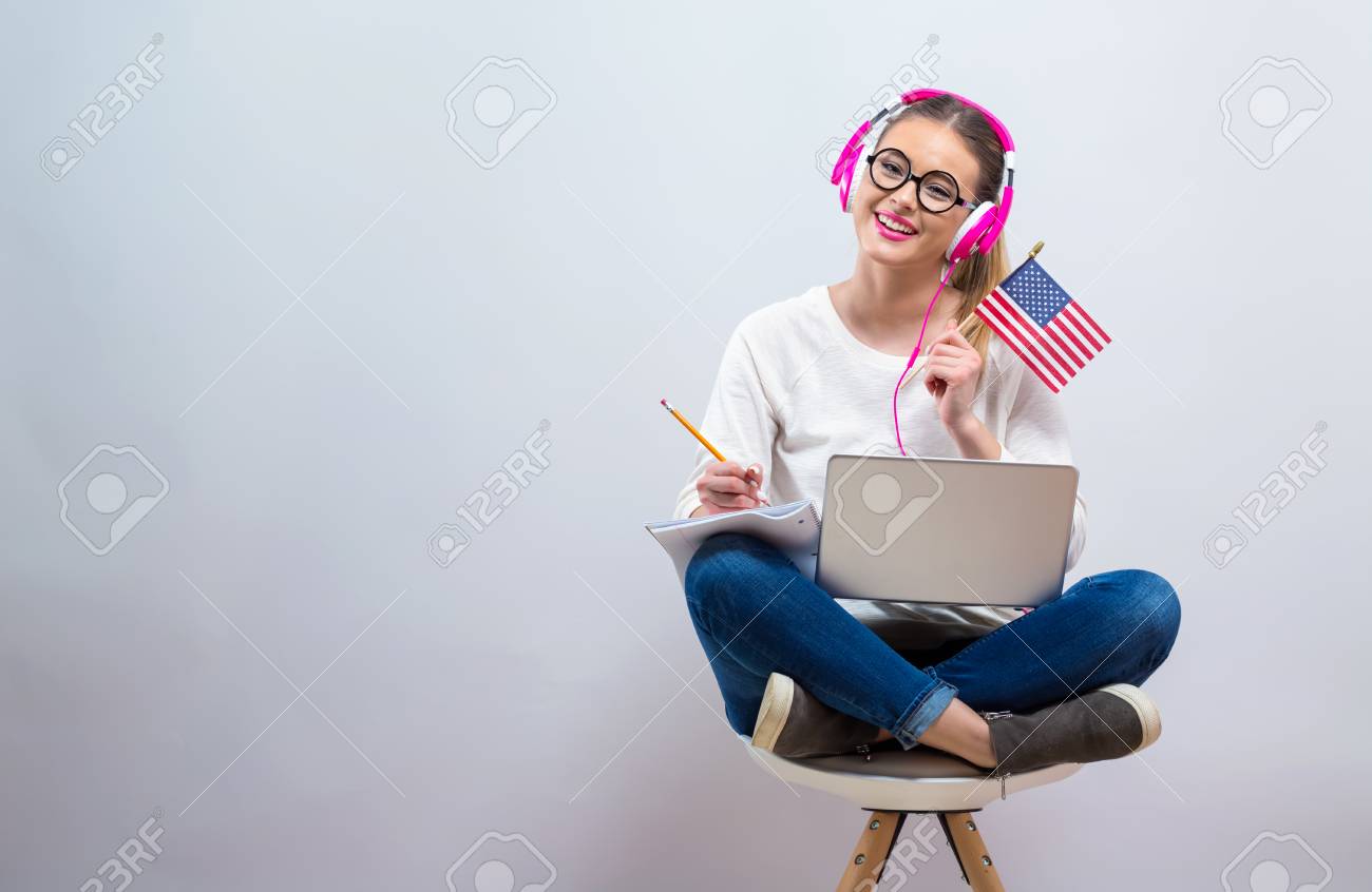 Young woman with USA flag using a laptop computer on a gray background - 111826393 Young woman with USA flag using a laptop computer on a gray background - 111826393