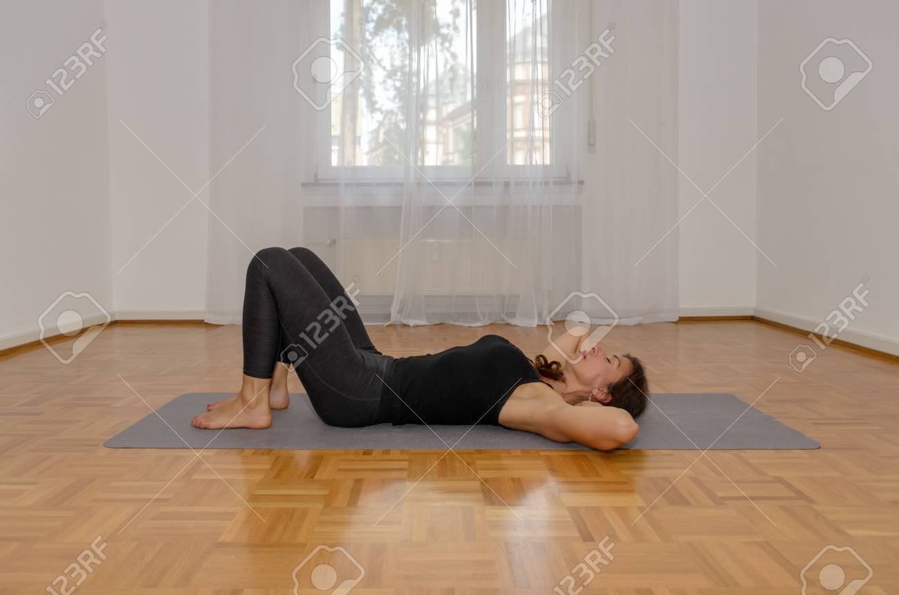 Woman Working Out At Home Relaxing On Her Back On A Mat On The