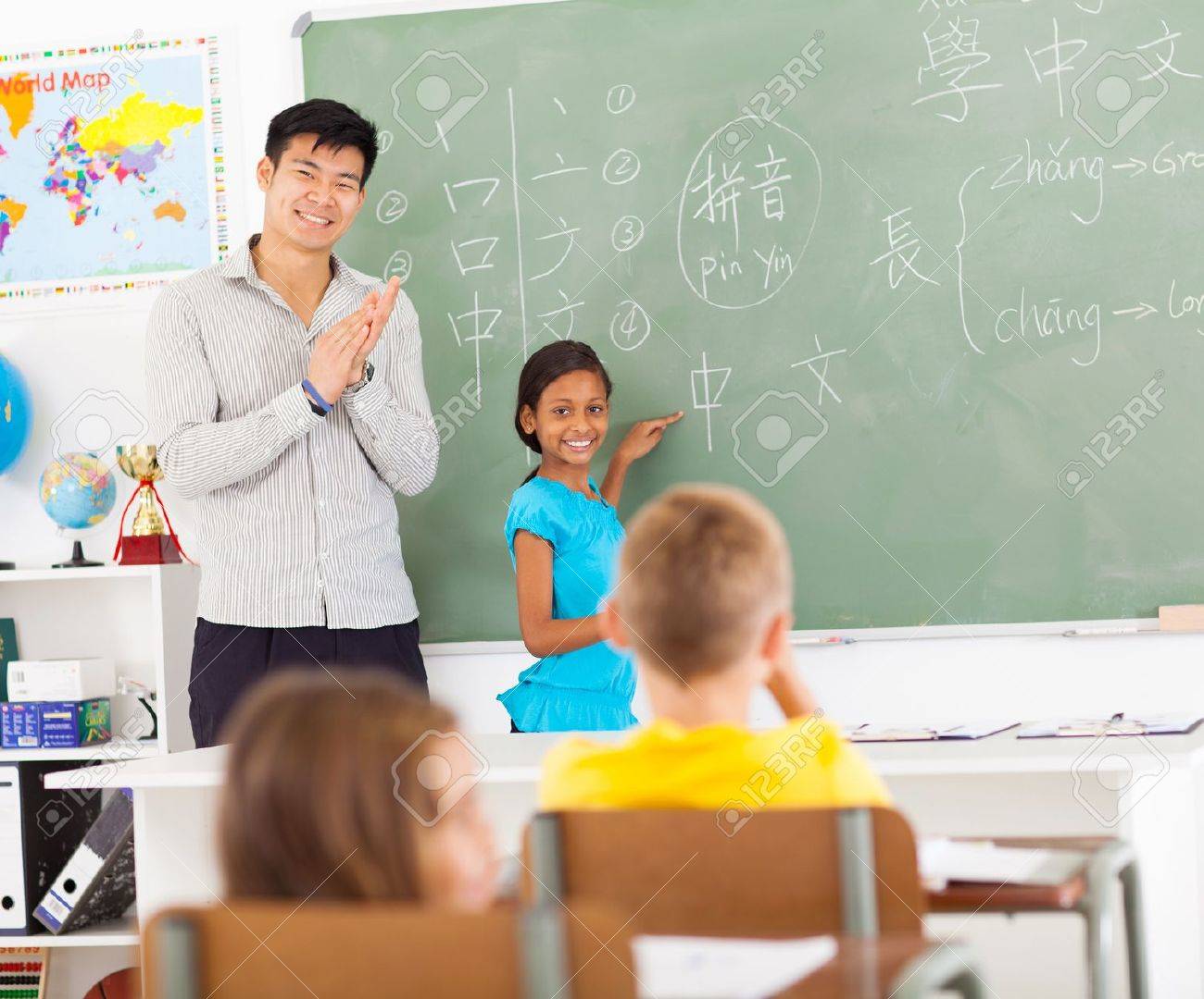 小学校の先生の若い女の子は黒板に中国語の単語を書いた後に拍手 の写真素材 画像素材 Image