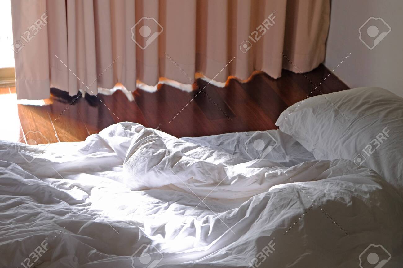 Unmade White Bed On Shiny Wood Floor Stock Photo Picture And