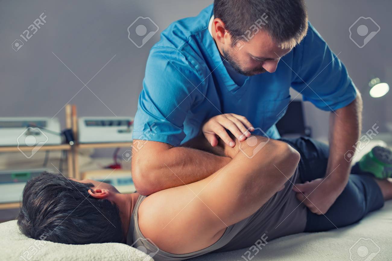 Physiotherapist doing healing treatment on man's back. Therapist wearing blue uniform. Osteopathy. Chiropractic adjustment, patient lying on massage table - 106884169 Physiotherapist doing healing treatment on man's back. Therapist wearing blue uniform. Osteopathy. Chiropractic adjustment, patient lying on massage table - 106884169