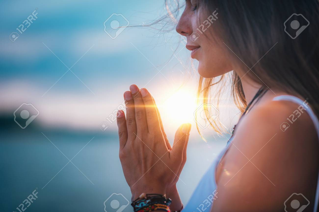 Young woman meditating with her eyes closed, practicing Yoga with hands in prayer position. - 115177780 Young woman meditating with her eyes closed, practicing Yoga with hands in prayer position. - 115177780