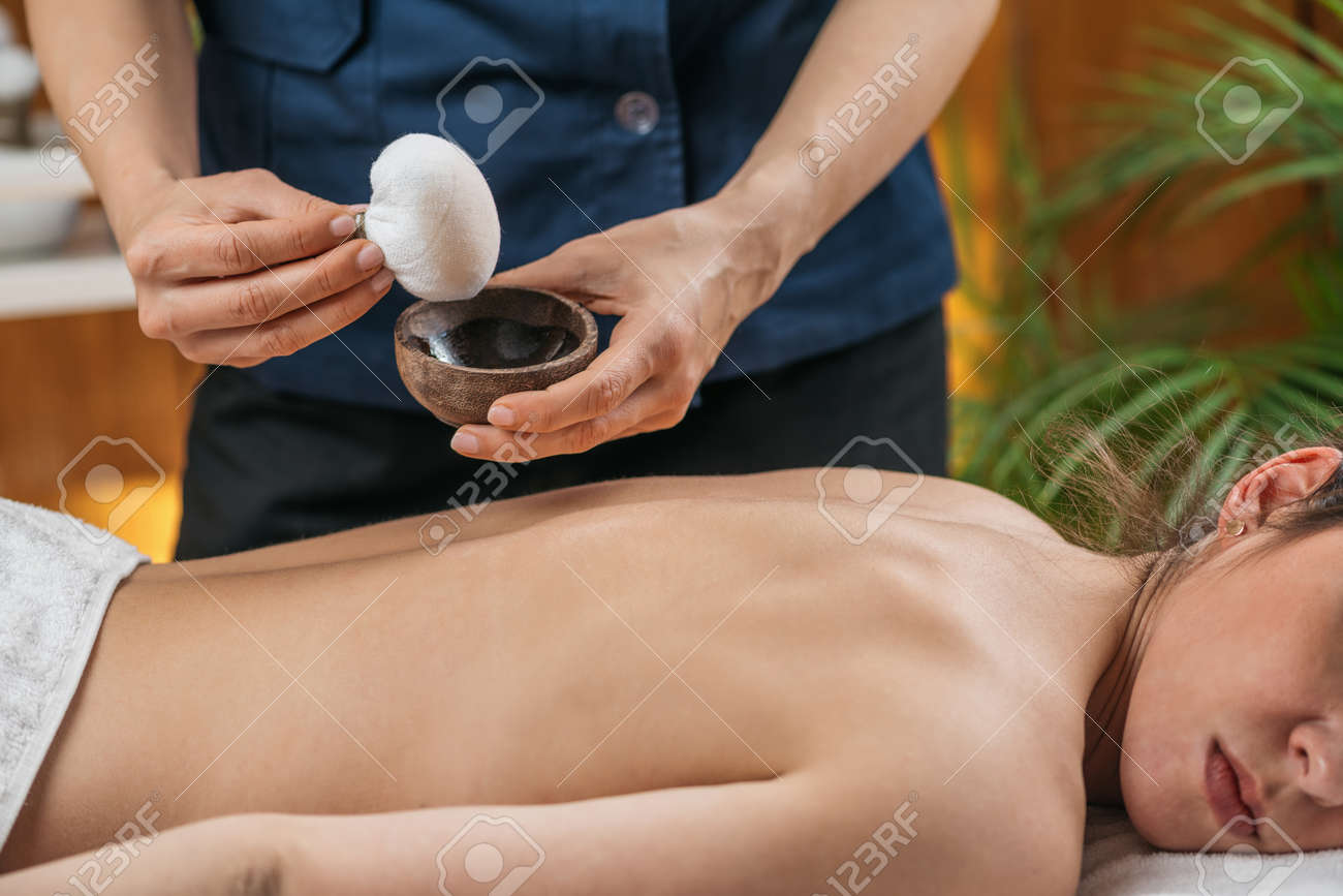 Kizhi or Herbal Bags Ayurveda Massage. Ayurvedic massage practitioner dipping cotton-wrapped herbal bundle into aromatic oil. - 169297520 Kizhi or Herbal Bags Ayurveda Massage. Ayurvedic massage practitioner dipping cotton-wrapped herbal bundle into aromatic oil. - 169297520
