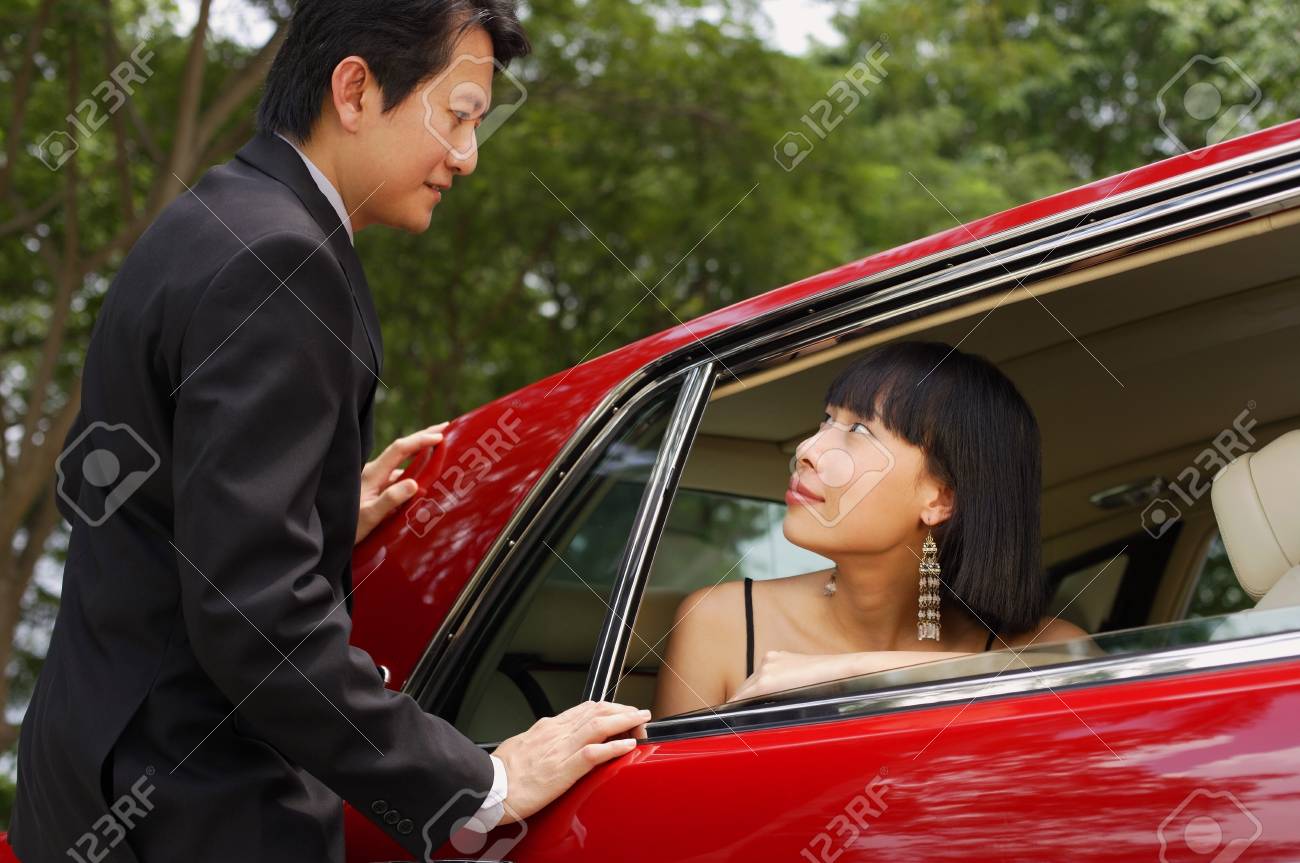 赤い車の女男の車のドアの横に立って の写真素材 画像素材 Image