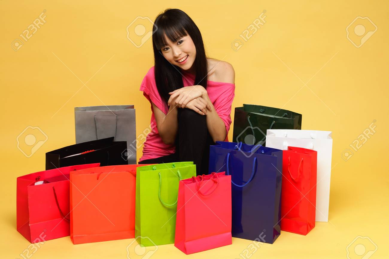 Young Woman Surrounded By Shopping Bags Kneeling On Floor Stock